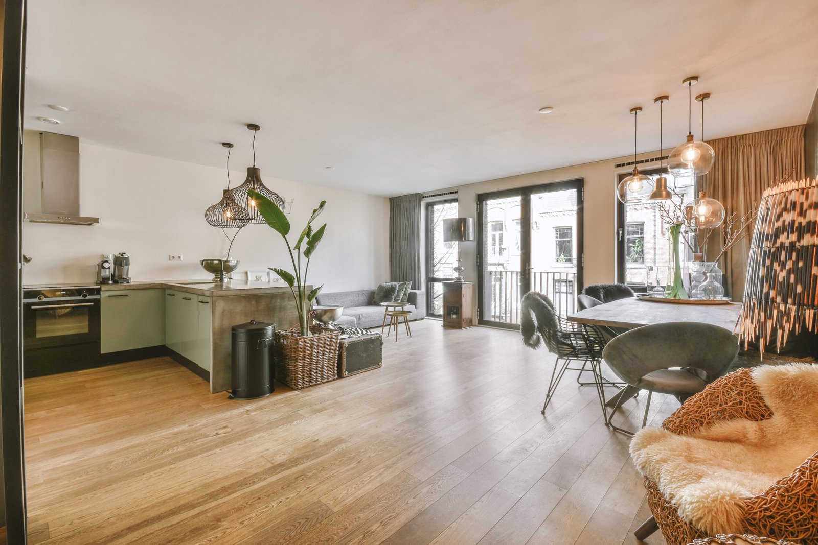 Interior of spacious light dining room and elegant chandelier located near kitchen with modern furniture and appliances